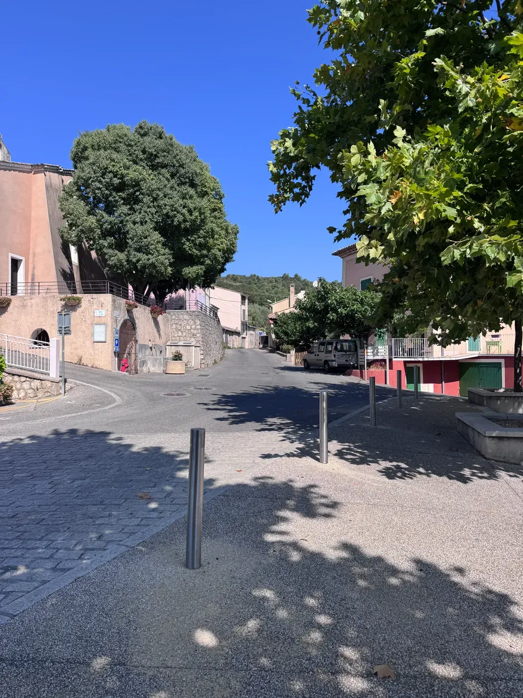 Une rue en pente du centre ancien de Villeneuve, bordée de maisons aux façades colorées.